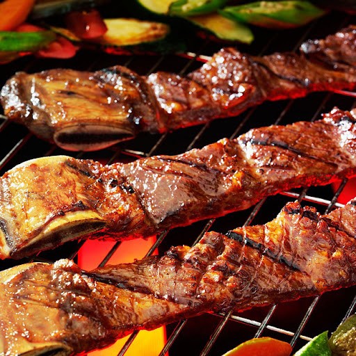 Sườn bò nướng trên vỉ than, mặt thịt xém vàng